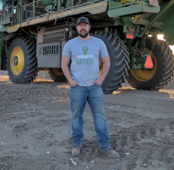 Willem Hoffman standing in a field in front of a John Deere cotton picker