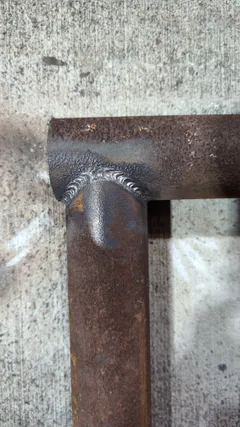 Close-up of a saddle-cut pipe joint with a clean wraparound weld