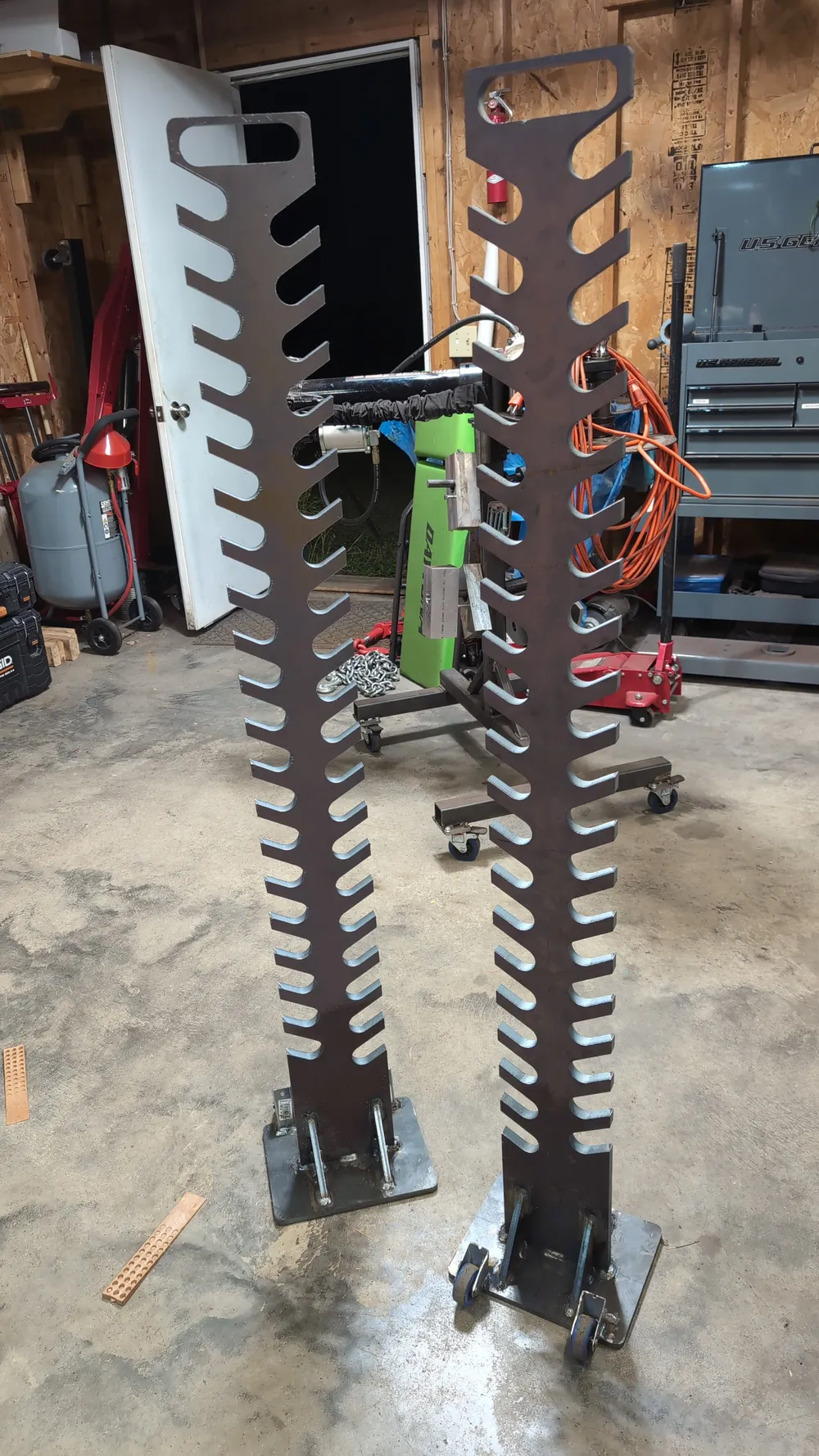 Two torque trees in the shop: a heavy-duty 54-inch model on casters with a handle, next to a standard model on a fixed base plate